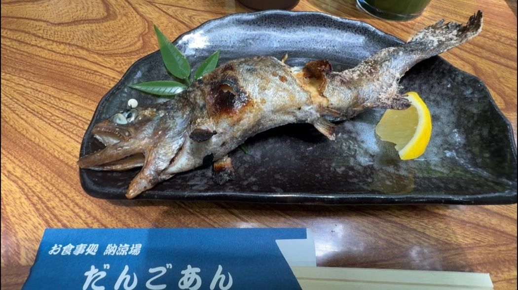 黒い皿に盛られた一尾のヤマメの塩焼き