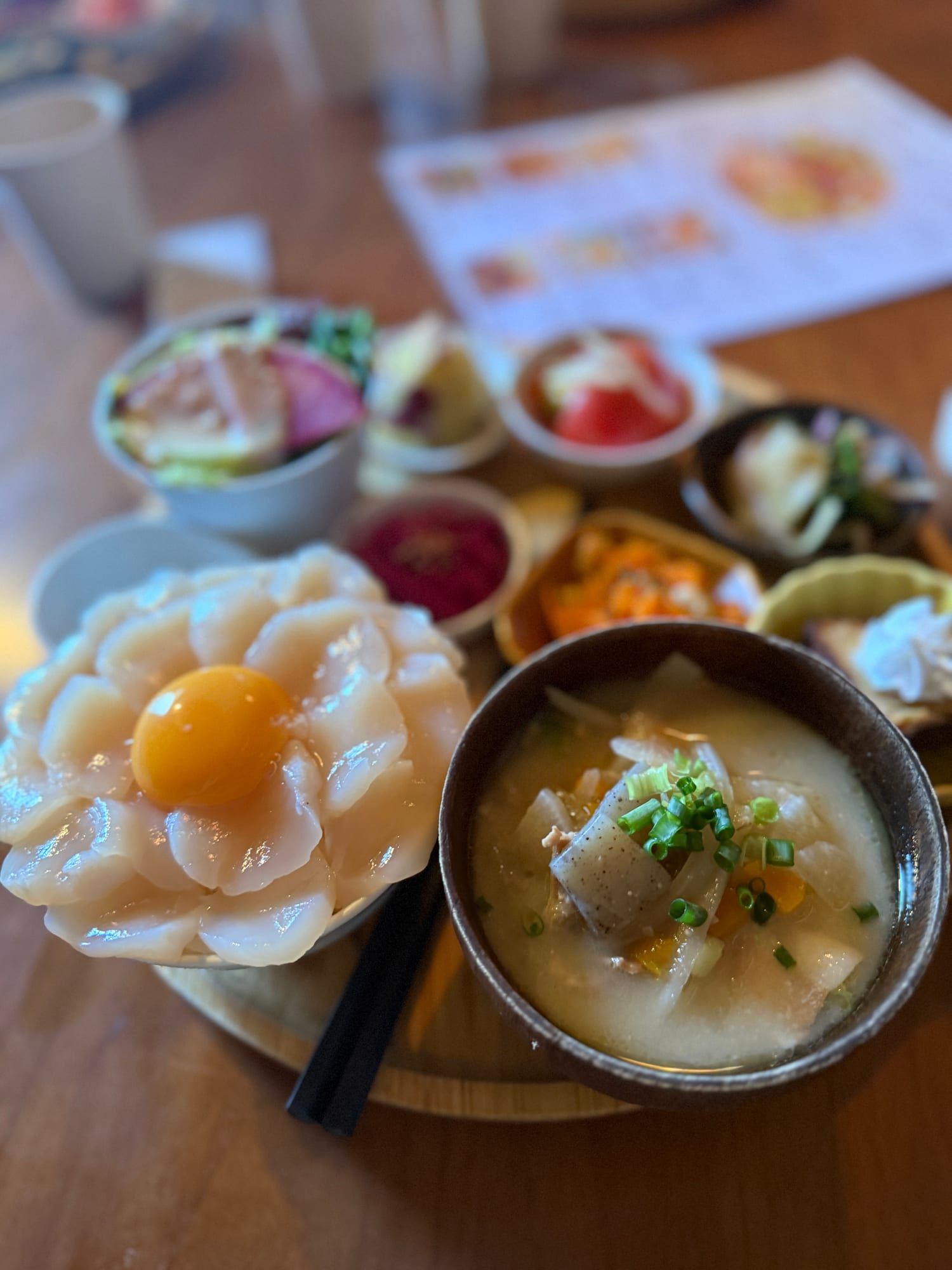 花びらのようにホタテが並び、中央に卵黄をのせた丼と豚汁