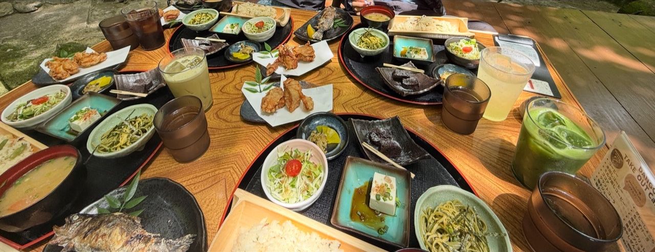 ヤマメや竹の器のご飯、小鉢、飲み物が並んだテーブル