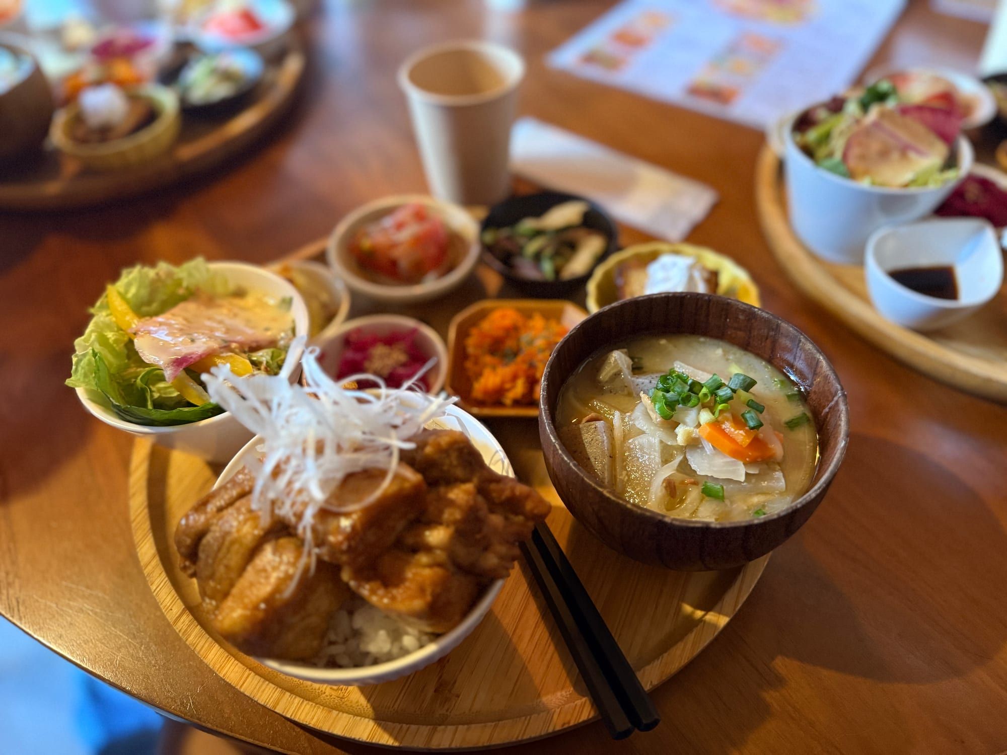 丼と豚汁の周りにサラダや色とりどりの野菜の小鉢が並ぶランチ