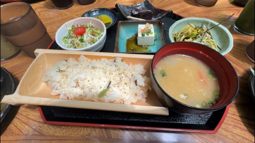 竹筒を割ったような器に盛られた炊き込みご飯と汁物、小鉢