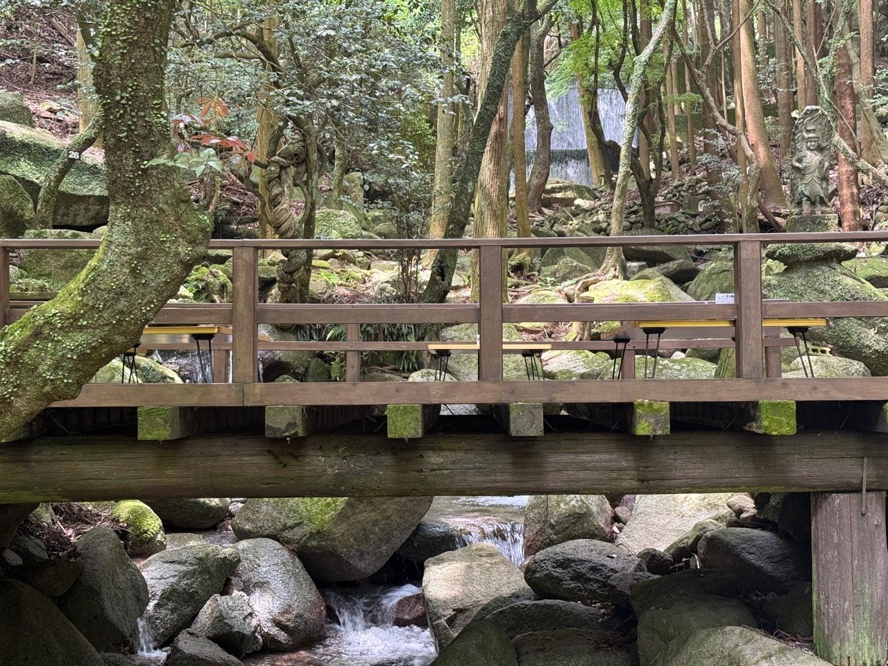 木々と渓流に囲まれ、奥に滝が見えるだんごあんの納涼場