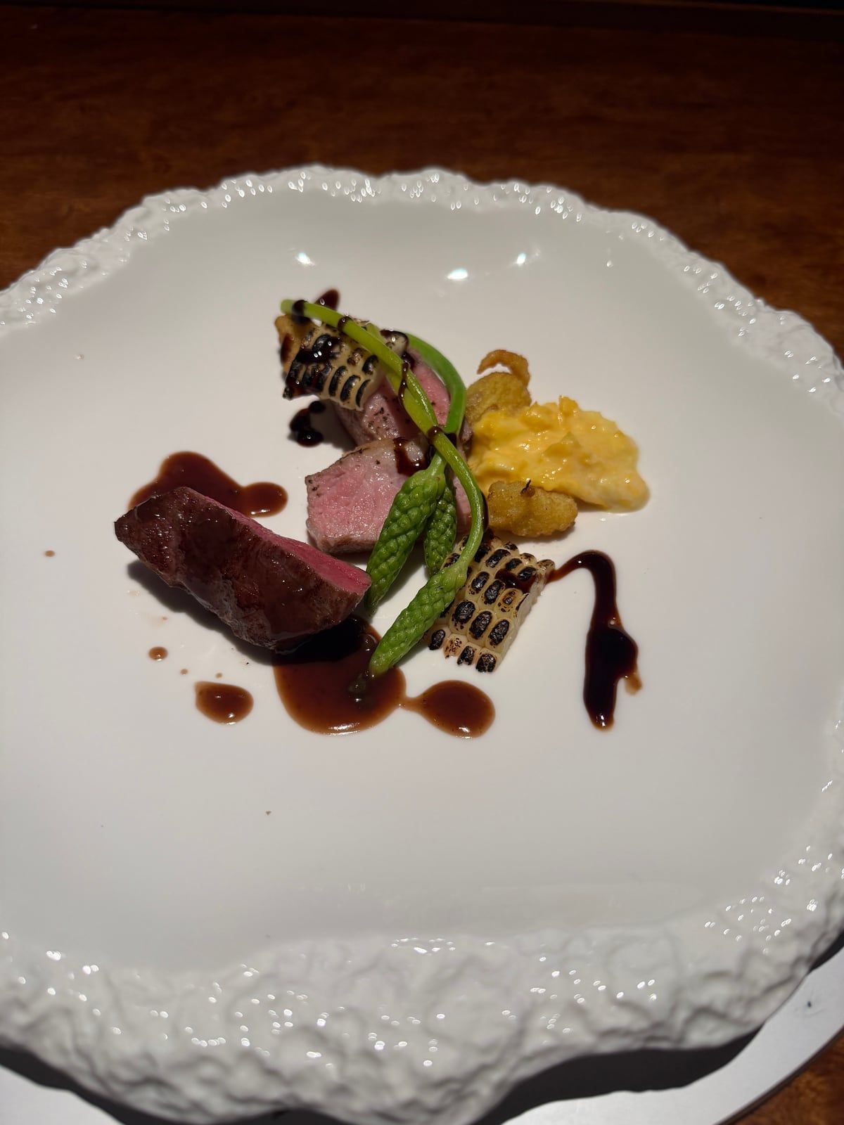 肉と焼き野菜に濃い色のソースを添えた料理
