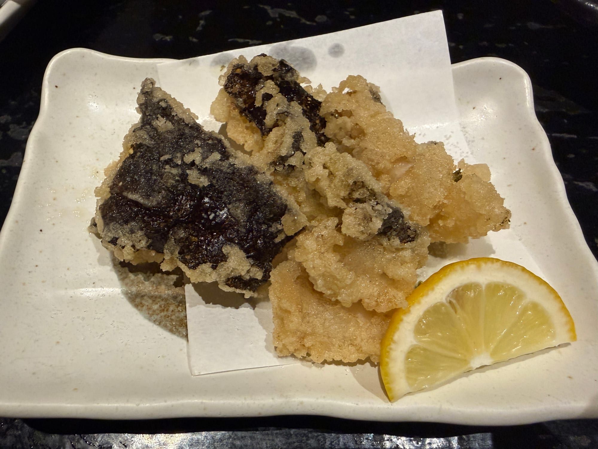 白い皿に盛られた、うつぼの天ぷらとレモン